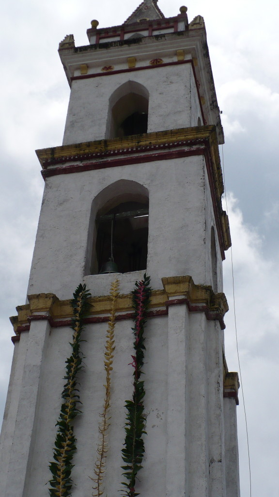 Bell tower of the catholic church decorated with garlands of flowers.